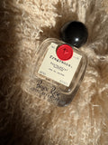 A 50 ml glass perfume bottle with black spherical cap, black text, a paper label and wax seal.