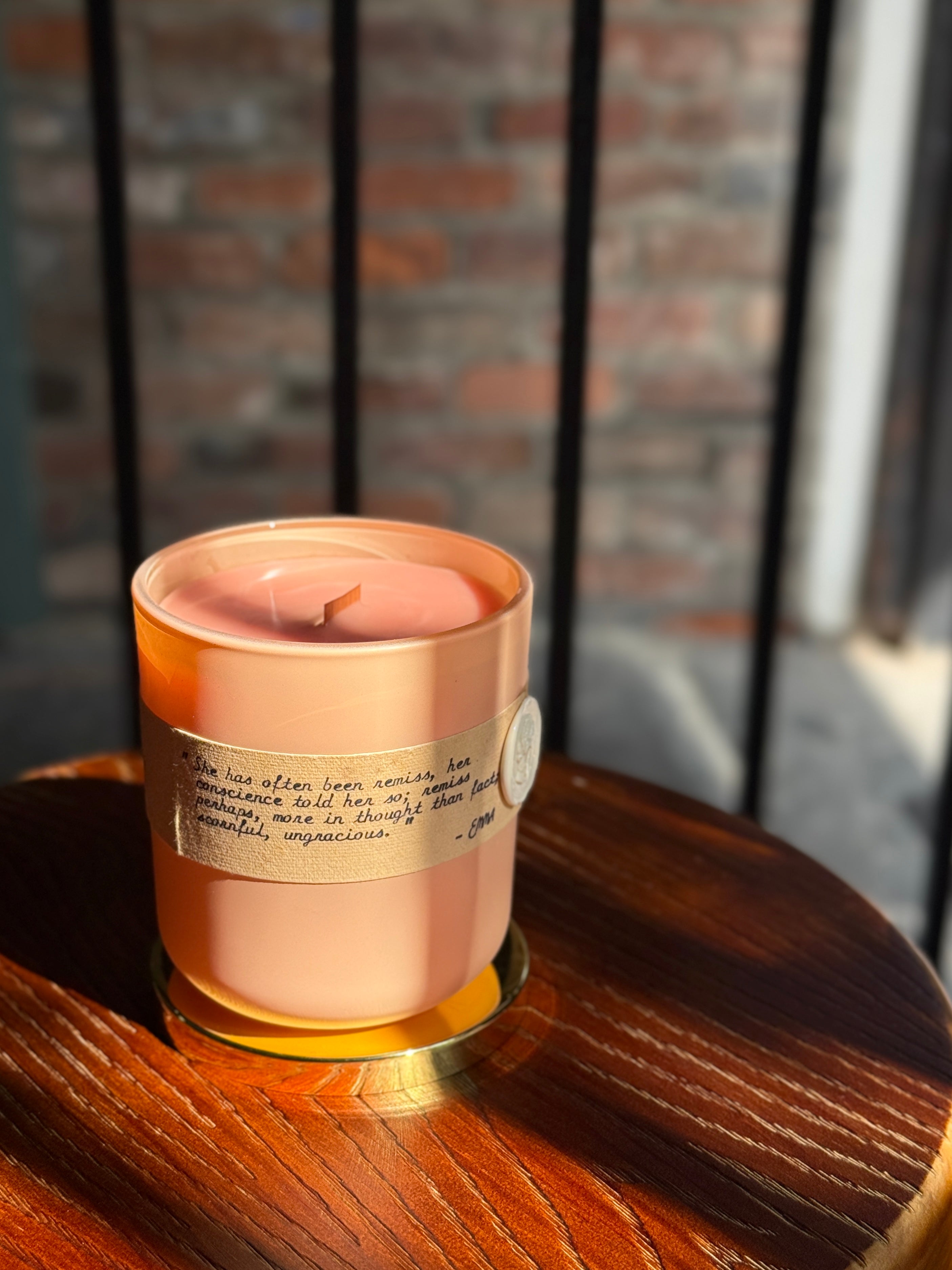 Top view of Bayou Rose Badly Done, Emma candle with wooden wick and peach colored wax with Jane Austen quote on label