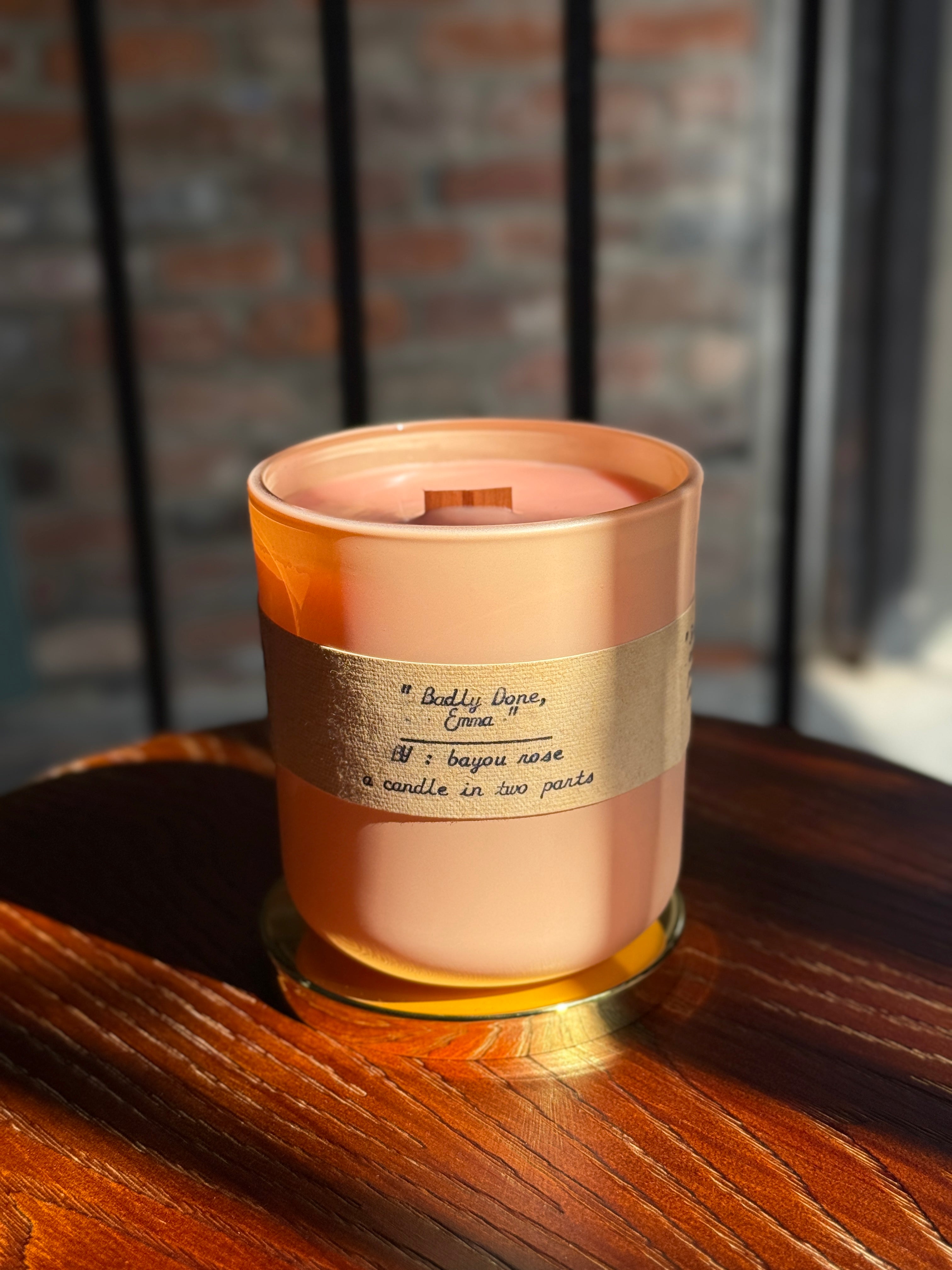 Bayou Rose Badly Done, Emma candle | lemon vanilla honey scented refillable candle in peach glass vessel on warm wood surface 