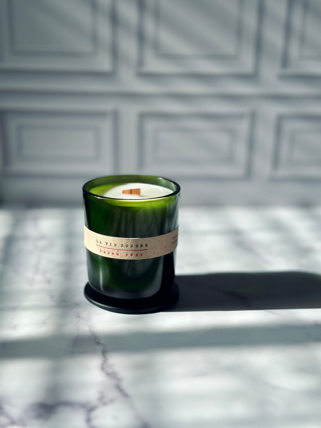La Vie Boheme luxury scented candle green glass vessel with fabric label and wooden wick, side angle on marble — Bayou Rose French Quarter